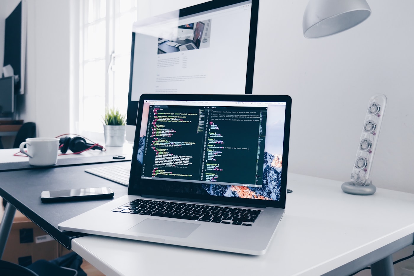 Laptop showing code and a website in a design workspace