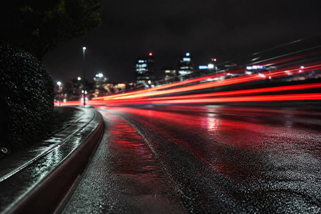 Night traffic on wet pavement, suggesting speed and people leaving a slow site